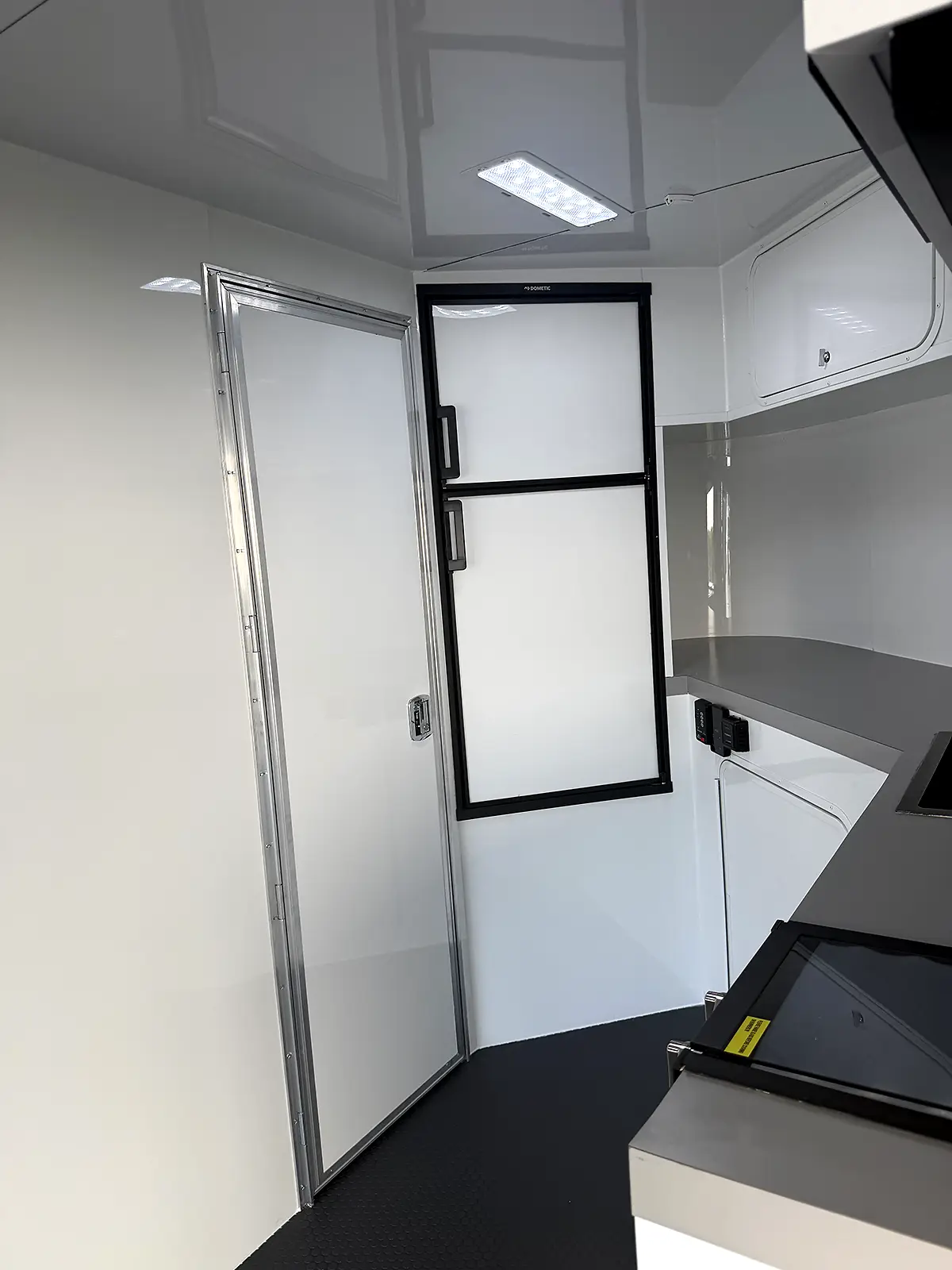 Living quarters interior with refrigerator, overhead cabinets and interior door