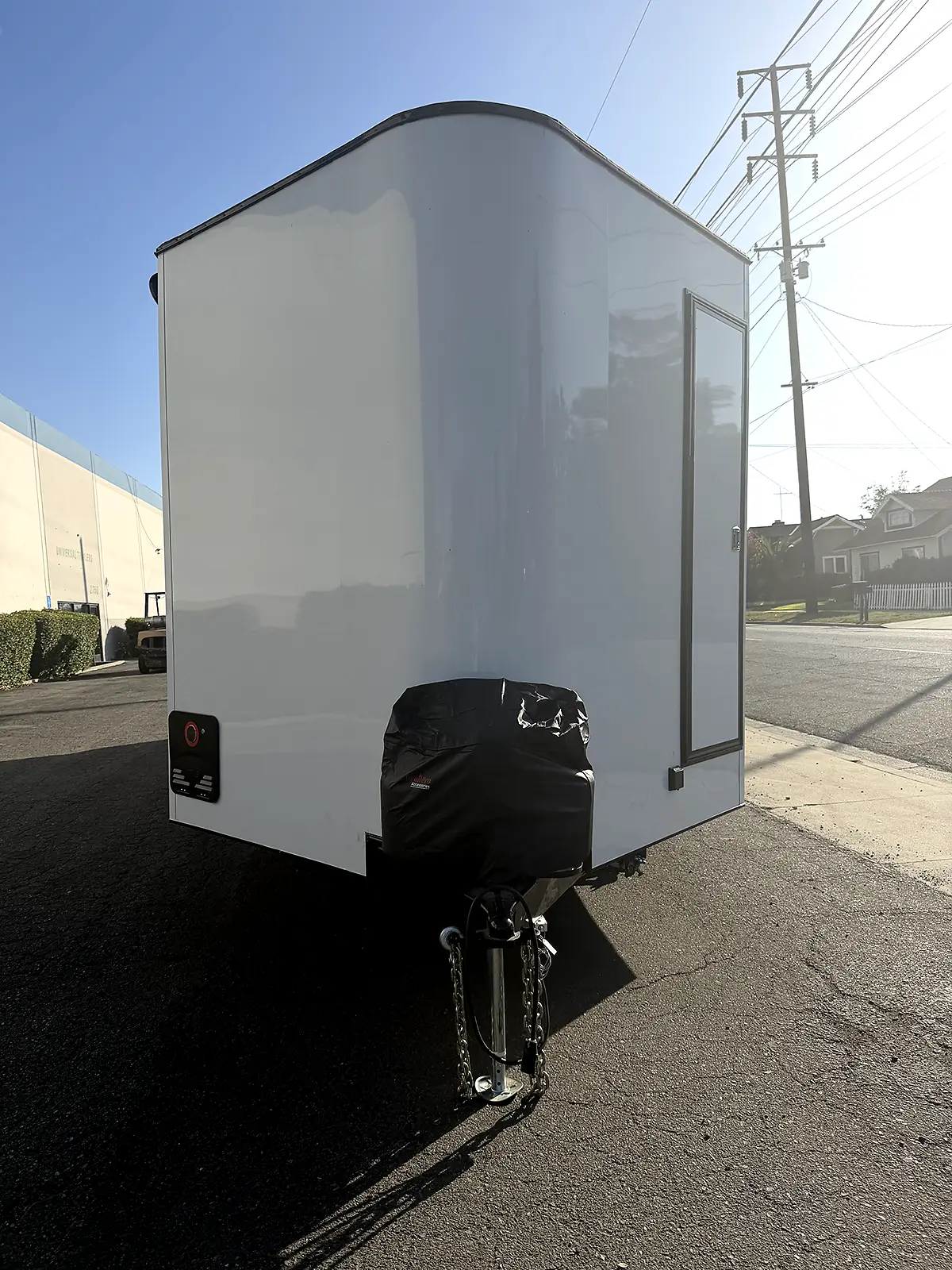 Front view of the white living quarters trailer with entry door and hitch