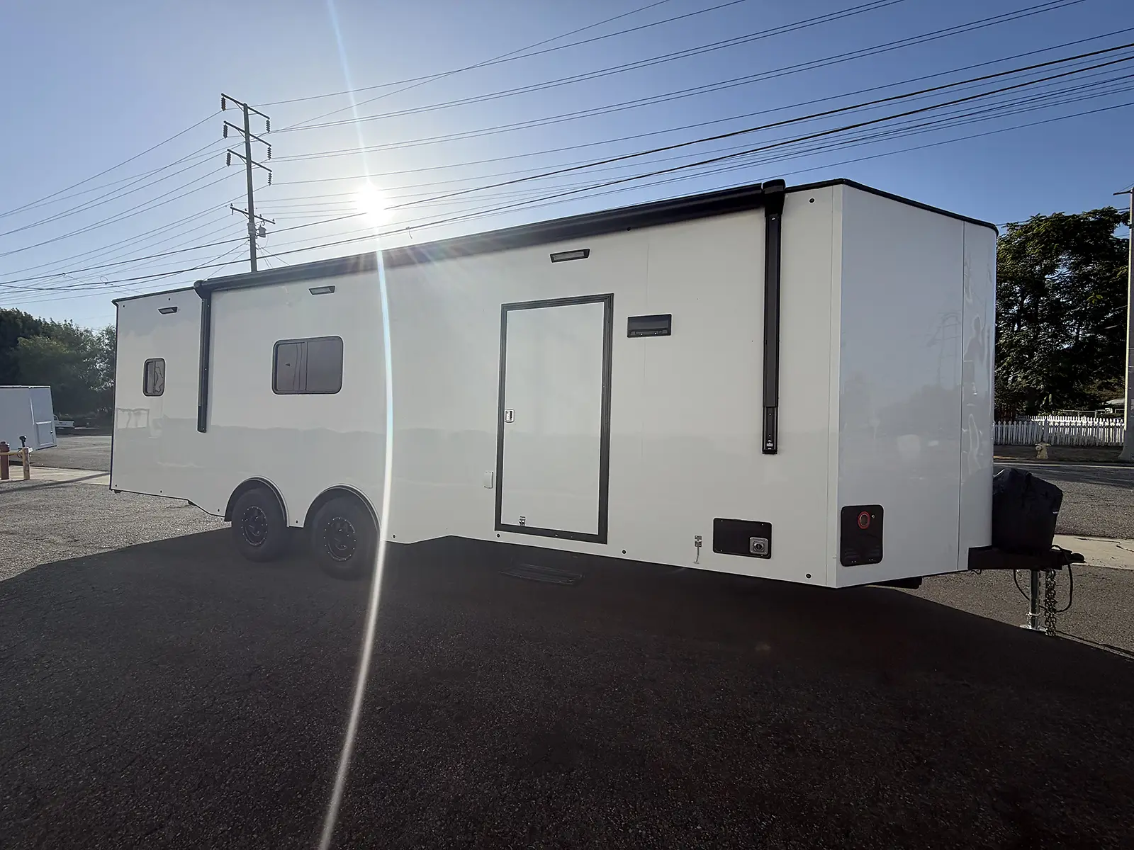 White tandem-axle living quarters trailer with side entry and retracted awning