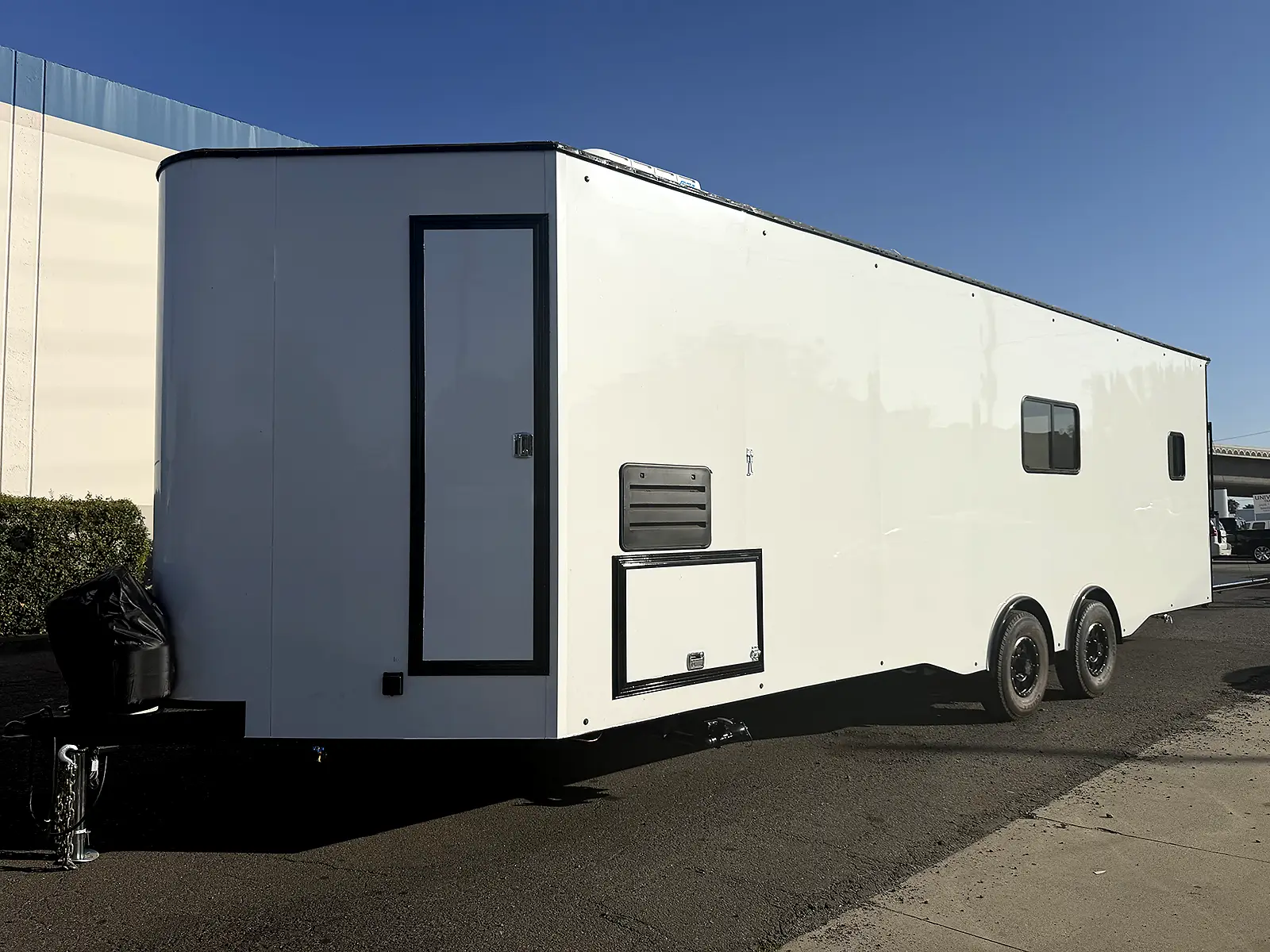 Front and side view of the living quarters trailer with utility compartments and windows