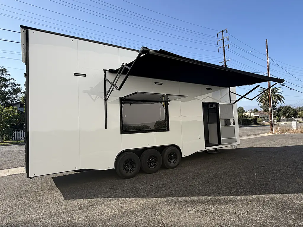 White triple-axle stacker trailer with extended awning and open side entry